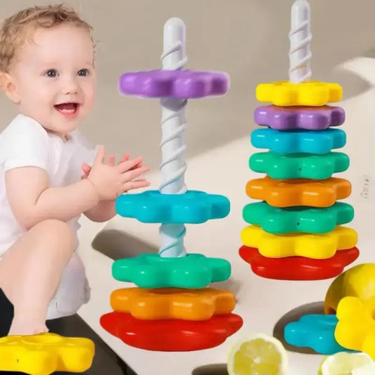 Colorful stacking spinning toy with white spiral rod and multi-tier discs, held by toddler