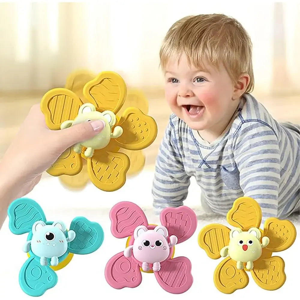 A smiling toddler playing with colorful suction cup bath toys shaped like animals, featuring pink, blue, and yellow colors.
