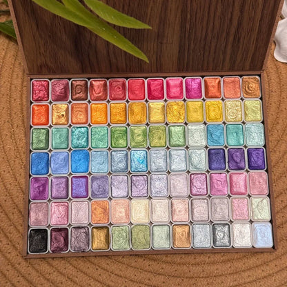 120 glitter watercolor paints in a wooden box, arranged in a grid with vibrant colors and metallic finishes.
