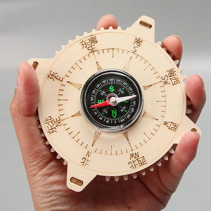 Wooden compass with a black dial, held in a hand, featuring cardinal directions marked in Chinese characters.