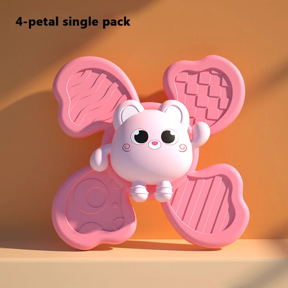 Pink 4-petal suction cup toy with a cartoon character in the center, featuring textured surfaces for tactile play.