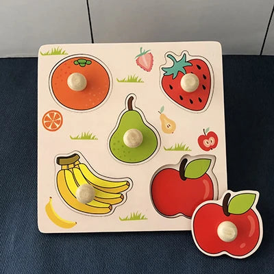 Wooden puzzle board featuring colorful fruit shapes: orange, strawberry, pear, banana, and apple with knobs for easy