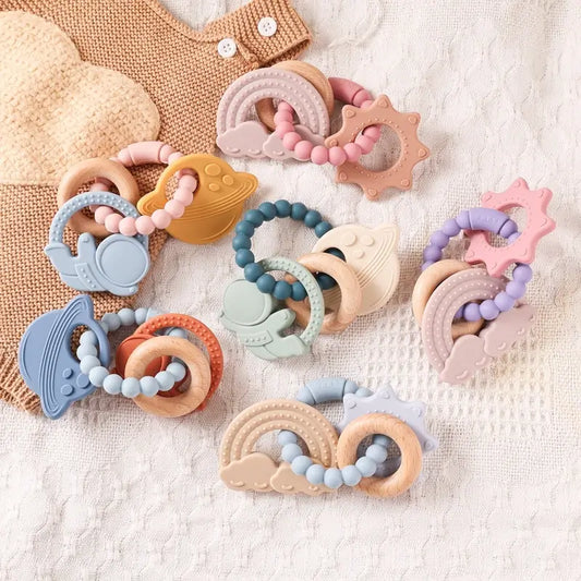 Colorful silicone teething rings in various shapes including animals and rainbows, with beads in pastel colors.