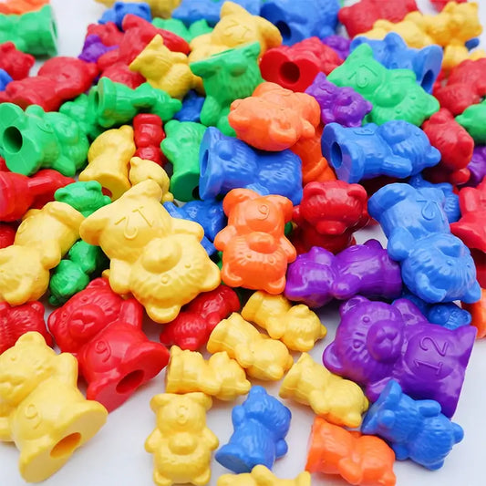 Colorful plastic counting bears in red, blue, yellow, green, and purple, scattered on a white surface.