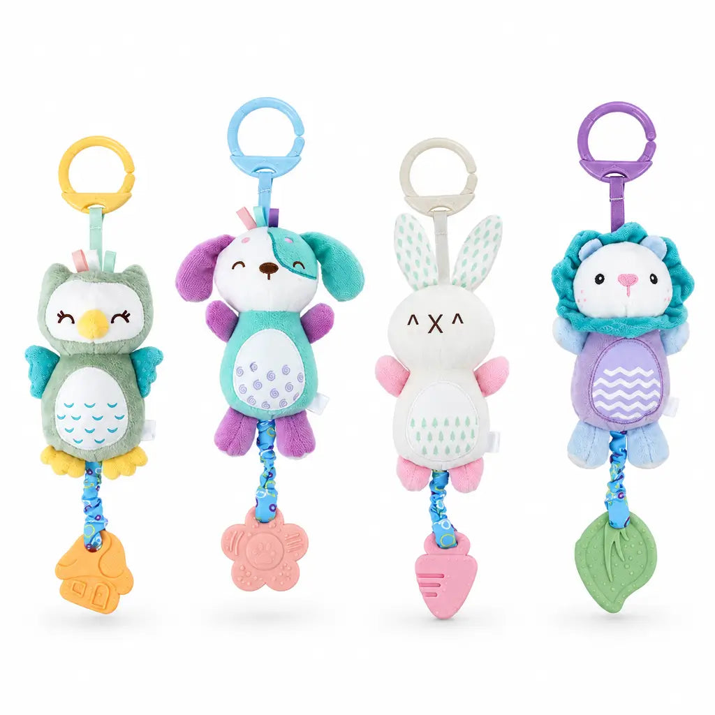 Four soft plush baby keychain toys in different animal designs are displayed on white pedestals against a warm beige background. The toys include an owl, a dog, a bunny, and a lion, each with a colorful ring handle and hanging toy at the bottom.
