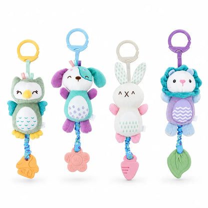 Four soft plush baby keychain toys in different animal designs are displayed on white pedestals against a warm beige background. The toys include an owl, a dog, a bunny, and a lion, each with a colorful ring handle and hanging toy at the bottom.