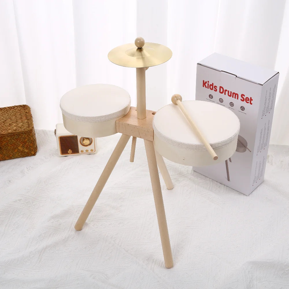 Kids drum set with two white drums, a cymbal, and wooden legs, next to a box labeled 'Kids Drum Set'.