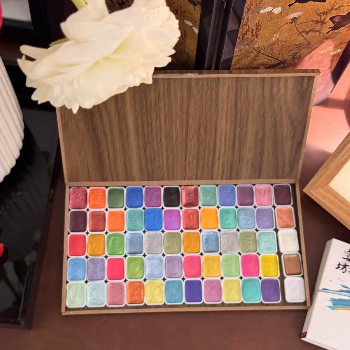 Wooden box containing 60 glitter watercolor paints in various colors, arranged neatly.