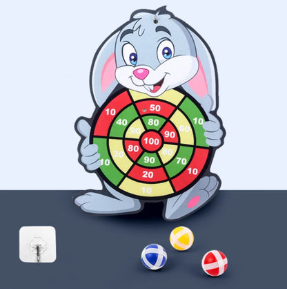 Cartoon rabbit holding a colorful dart board with sticky balls in red, yellow, and blue on a gray surface.