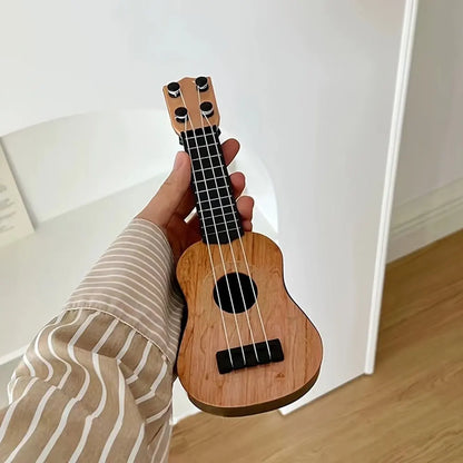 Mini classical ukulele guitar toy held in hand, featuring a wooden finish and black strings, suitable for kids.