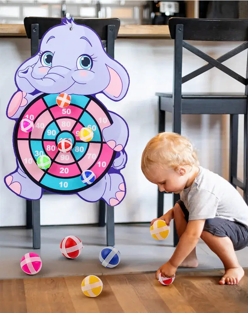 Cartoon elephant dart board with colorful sticky balls, child playing with balls on the floor, interactive toy.