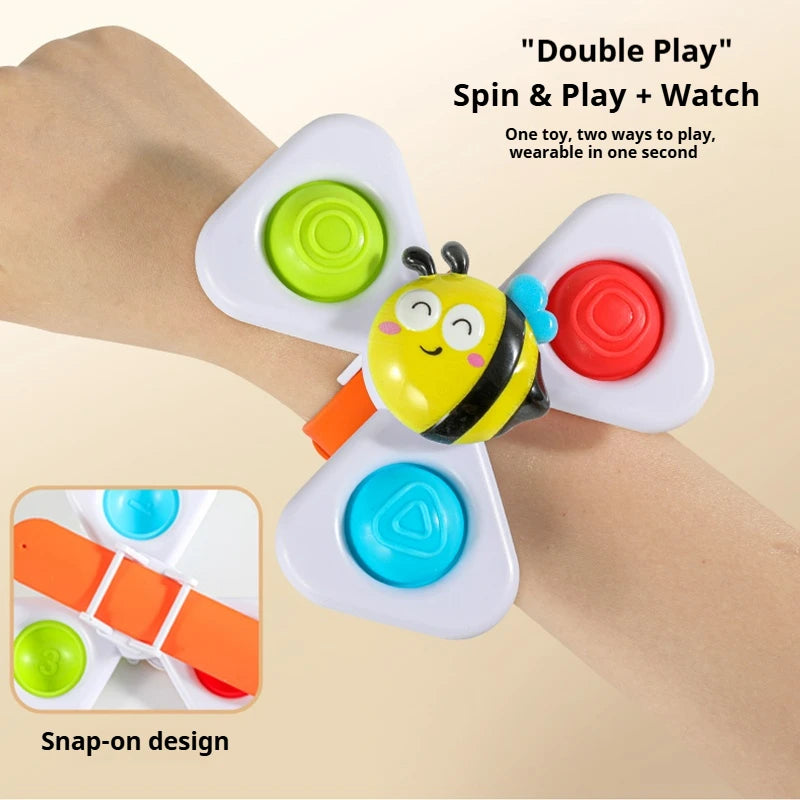 Colorful suction cup spinner toy with a cartoon bee, attached to a wristband, featuring buttons in blue and green.