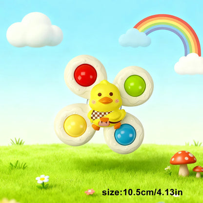 Colorful suction cup spinner toy featuring a yellow duck and bright buttons, set against a grassy background with clouds and
