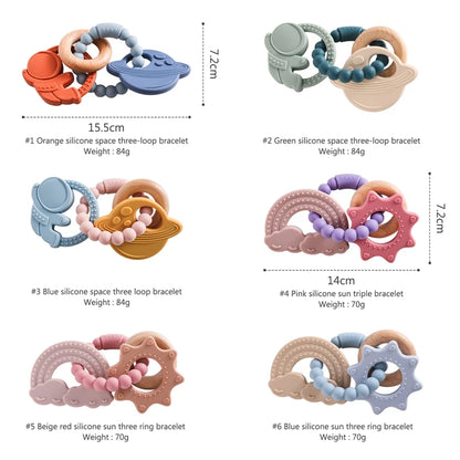 Four silicone teething rings in various colors and shapes, including planets and suns, with textured beads.