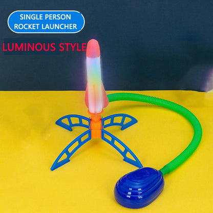 Colorful rocket launcher with illuminated tip, green hose, and blue stomp pad on a yellow background.