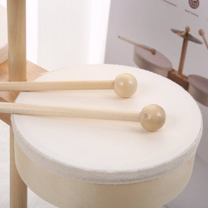 Wooden drumsticks resting on a white drum surface, part of a kids drum set with a light wood finish.