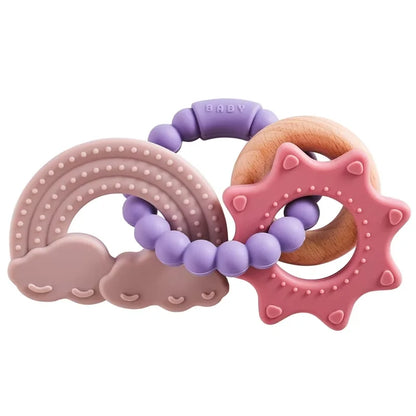 Silicone teether set featuring a rainbow, clouds, and sun shapes in pink, purple, and wood tones.