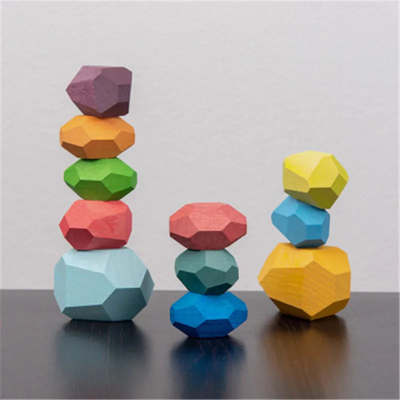 Colorful wooden stacking rocks in various shapes, arranged in two groups on a dark surface.