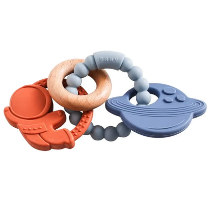 Silicone teether with astronaut, planet, and wooden ring, in red, blue, and natural colors, designed for babies.