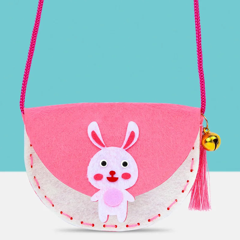 Pink and white felt shoulder bag with a rabbit design, featuring a bell and pink strap, suitable for kids.