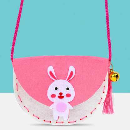 Pink and white felt shoulder bag with a rabbit design, featuring a bell and pink strap, suitable for kids.