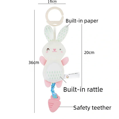 Soft stuffed animal rattle in bunny shape with pink and white colors, featuring a built-in rattle and safety clip.