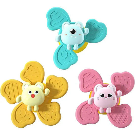 Three colorful baby bath toys featuring cartoon characters in yellow, blue, and pink with suction cups.