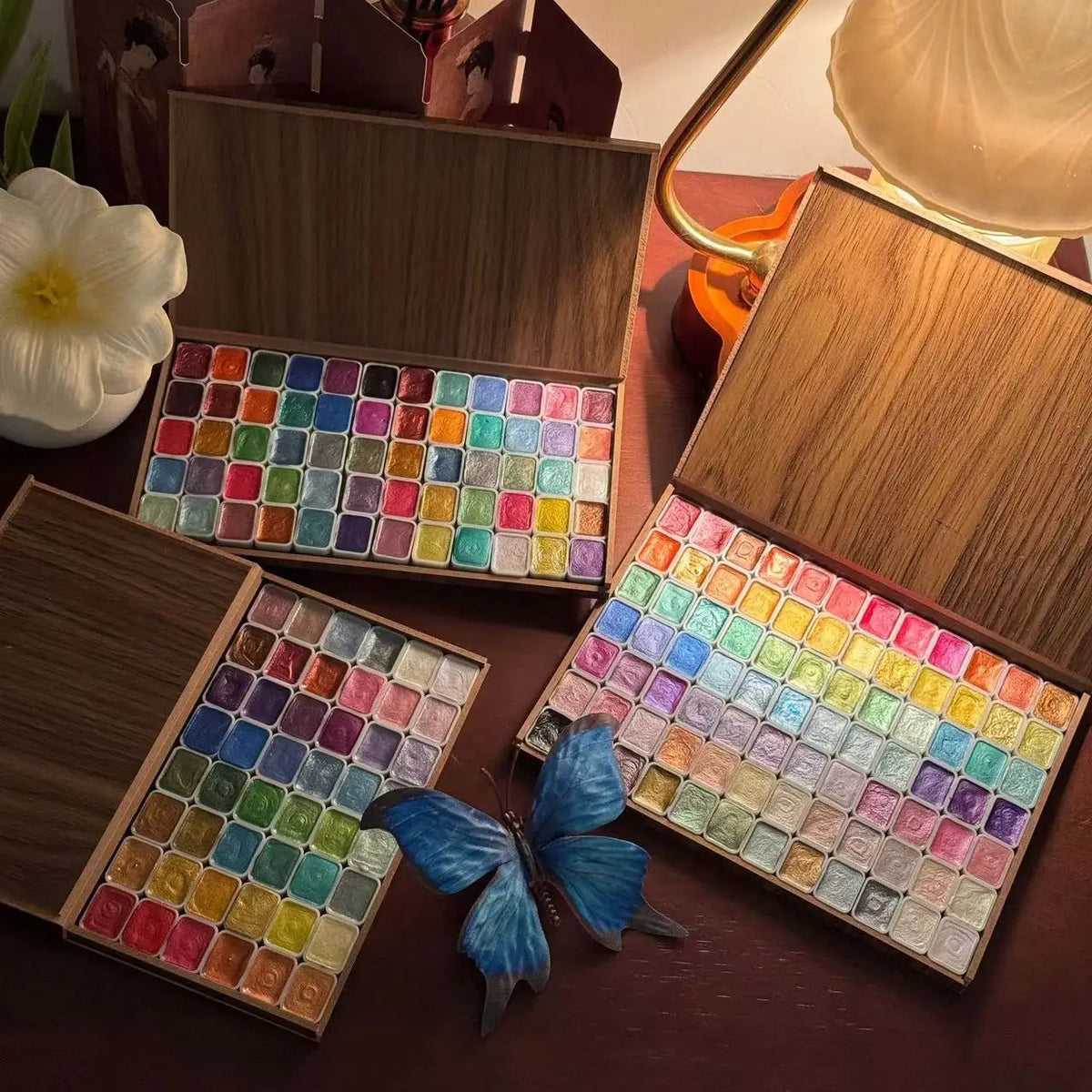 Set of 120 glitter watercolor paints in a wooden box, featuring vibrant colors arranged in three trays, with a butterfly