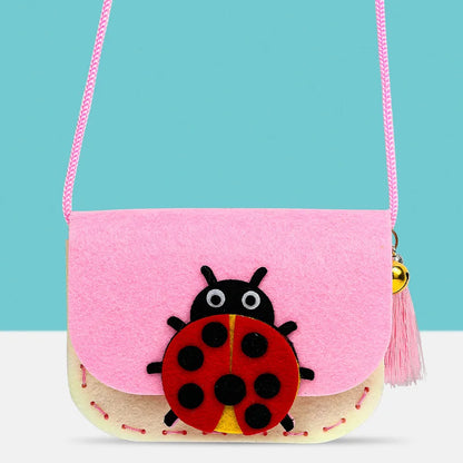 Pink and cream non-woven fabric shoulder bag with a ladybug design, featuring a pink strap and tassel.