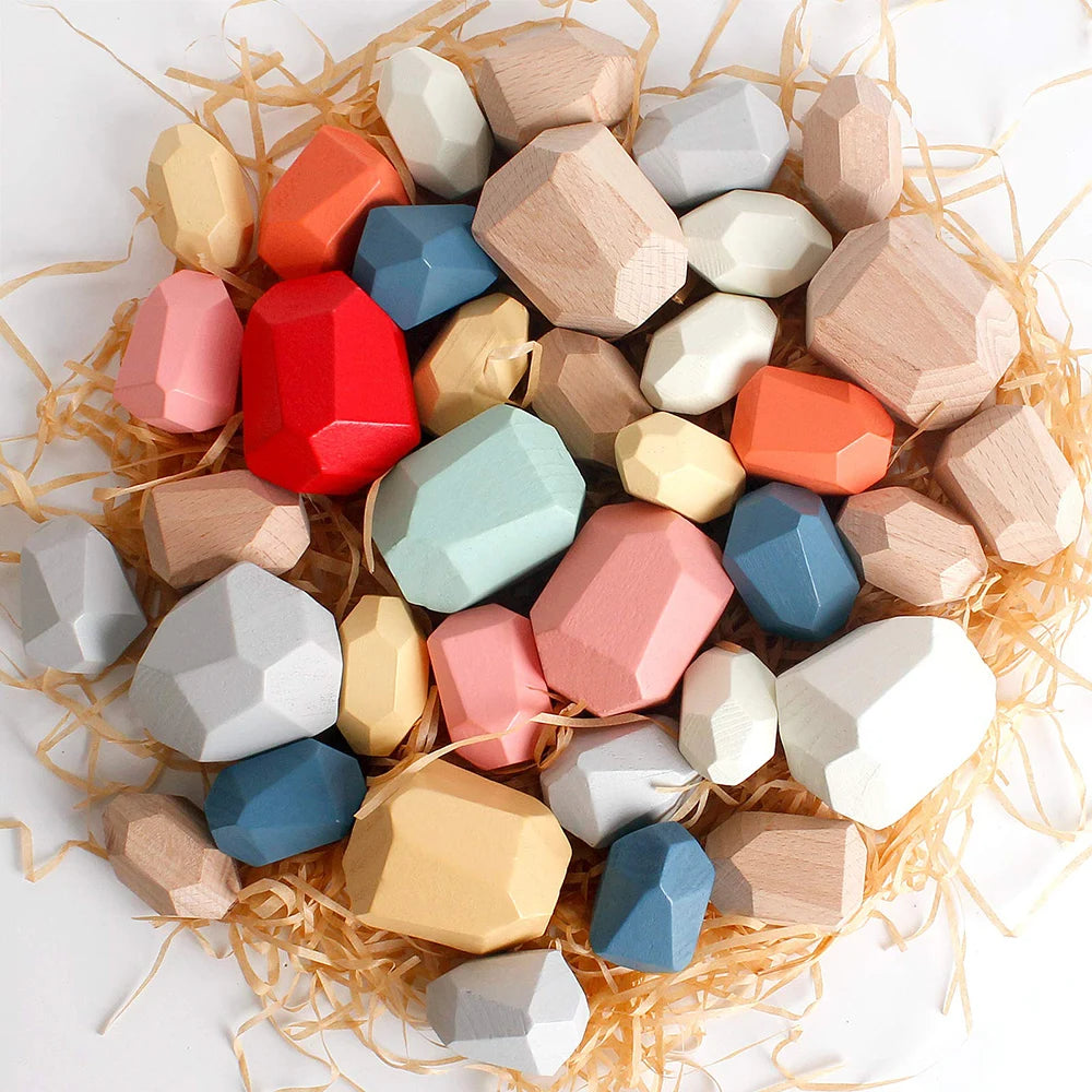 Colorful wooden sorting stacking rocks in various shapes and sizes, arranged on straw, suitable for toddler play.
