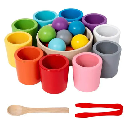 Colorful wooden sorting cups in various shades with balls and tools, including a wooden spoon and red tweezers.