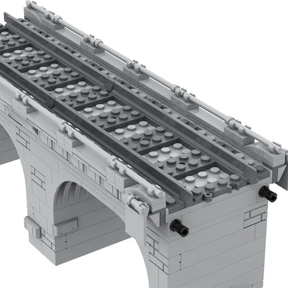 Gray building block model of a traffic bridge with train tracks, featuring detailed arches and connectors.